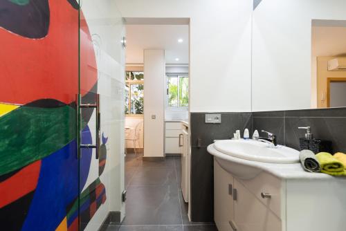 大加那利岛拉斯帕尔马斯Suites Garden Loft Miro的浴室设有水槽,墙上挂着色彩缤纷的绘画作品
