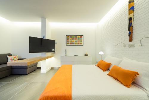 大加那利岛拉斯帕尔马斯Suites Garden Loft Miro的白色卧室配有一张带橙色毯子的大床