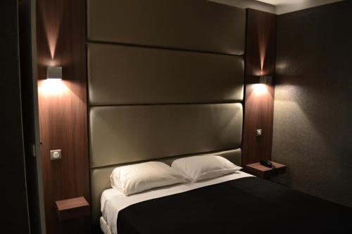戛纳科罗纳酒店的一间卧室配有一张带黑色床头板和两个灯的床。