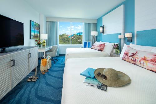 奥兰多洛伊斯蓝宝石瀑布度假酒店的酒店客房设有两张带帽子的床和一台电视