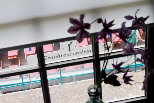 阿尔克马尔Wolf Hotel Kitchen & Bar的窗户上装有紫色花卉的花瓶