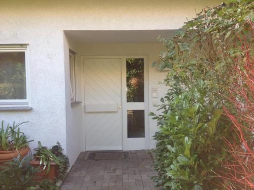 蒂宾根Gästezimmer bei Ingrid的白色的前门,有植物的房子