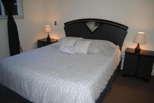 圣萨尔瓦多Apart Hotel Valle Verde的一间卧室配有一张带白色床单和两盏灯的大床