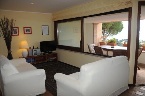 特雷维尼亚诺罗马诺萨巴提内斯公寓的客厅配有两把白色椅子和电视