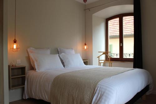萨维尔纳Le Manoir de l'Abbaye的一间卧室配有一张带白色床单的床和一扇窗户。