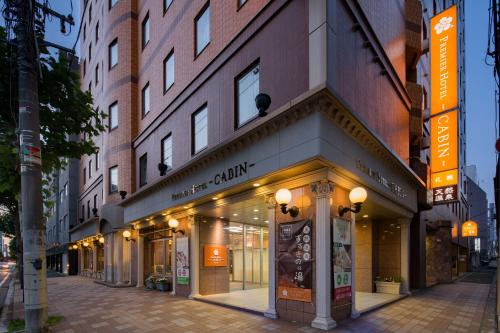 札幌普樂美雅飯店 -CABIN- 札幌 (Premier Hotel -CABIN- Sapporo)的城市街道上建筑物前面的商店