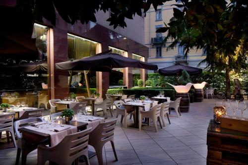 米兰星际利兹酒店的室外餐厅设有桌椅和遮阳伞。
