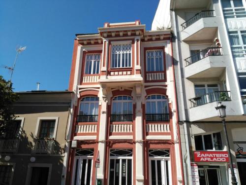 里瓦德奥Apartamentos San Roque的城市街道上一座粉红色的建筑,设有窗户