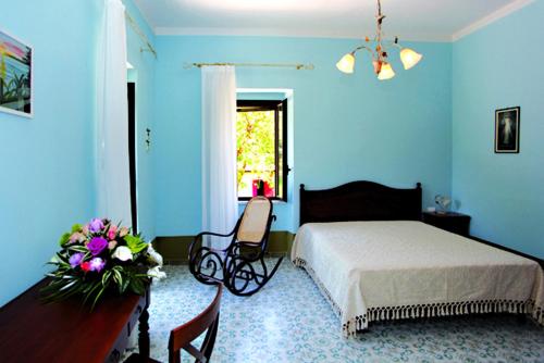 Rocca dʼEvandroIl Nibbio Reale Country House的蓝色的卧室,配有床和鲜花桌