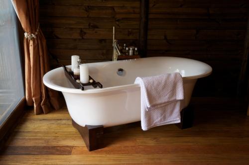 MkalinzuSerena Mivumo River Lodge的浴室铺有木地板,配有白色浴缸。