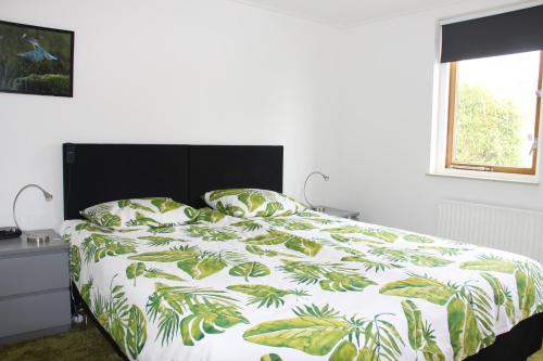 NieuwkoopGastenverblijf De Kapitein的一间卧室配有一张带绿色和白色棉被的床