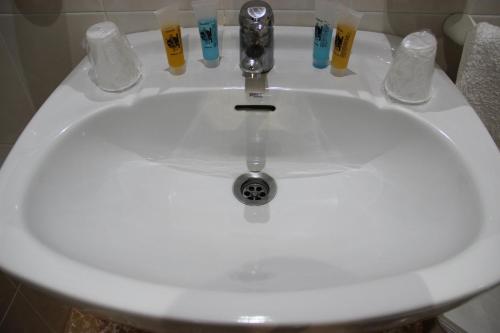 CarcabueyHostal la zamora的浴室水槽配有水龙头和4个饮酒杯