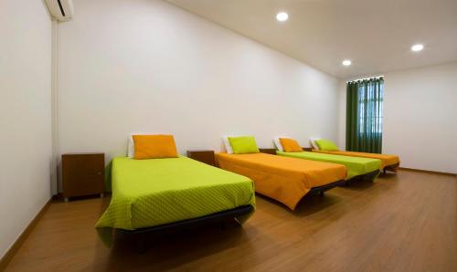 塞图巴尔Russo's Hostel的一间设有三张床的客房,配有绿色和橙色