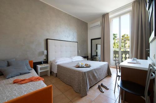 米兰德利西亚酒店的一间卧室配有一张床、一张桌子和一个窗户。