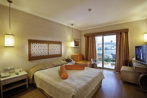 居姆贝特Royal Asarlik Beach Hotel的酒店客房,配有床和电视