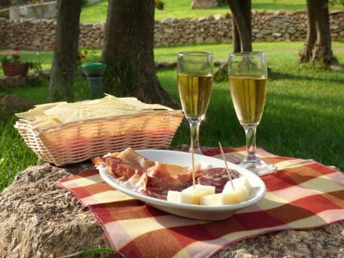 圣特奥多罗Agriturismo La Rocca Manna的盘子和两杯葡萄酒