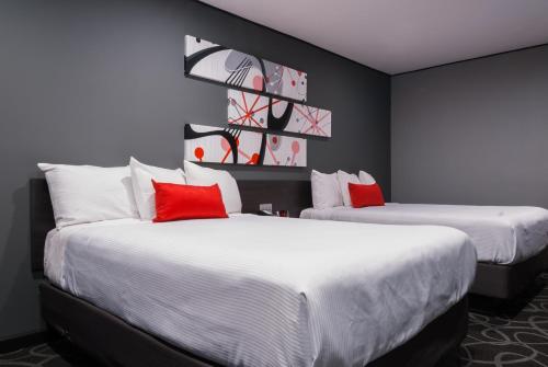 帕萨迪纳帕萨迪纳阿斯特罗酒店的两张位于酒店客房的床铺,配有红色枕头