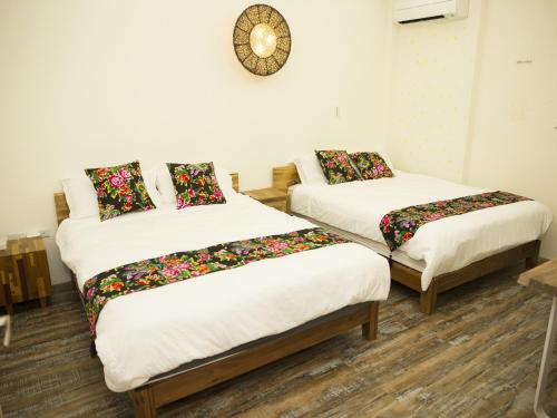 金湖镇柚木的家的一间设有两张床的客房和墙上的时钟