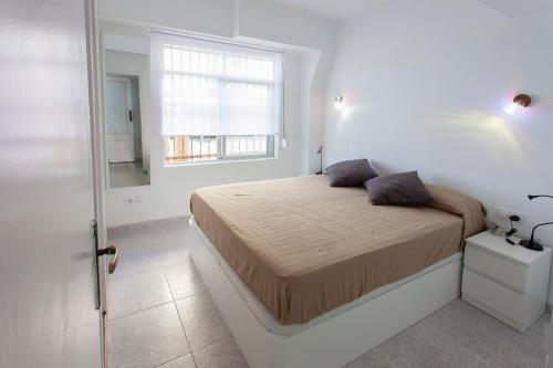 萨洛Apartamento Miramar的白色的卧室设有床和窗户