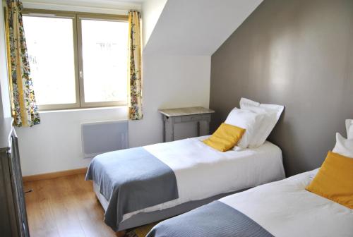 吉维尼Cottage Les Quatre Saisons的一间卧室设有两张床和窗户。