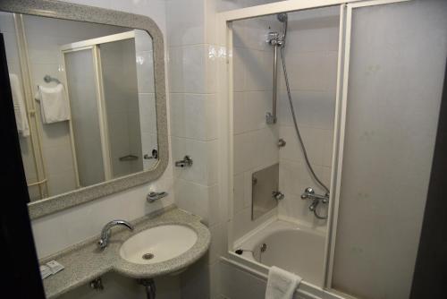 NašiceHotel Park的浴室配有盥洗盆和带镜子的淋浴