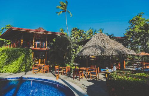 坦波Tambor Tropical Beach Resort- Adults Only的一个带游泳池和椅子的度假胜地和一座建筑