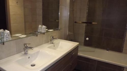 CarantillyLa Cocotte Gourmande的浴室配有水槽、淋浴和浴缸。