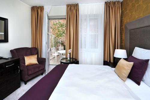布拉迪斯拉发阿普兰德佩鲁贾城市酒店的酒店的客房 - 带一张床、椅子和窗户