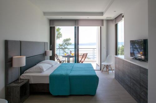 布雷拉Soho Apartments Brela的一间卧室配有一张床、一台电视和一个阳台