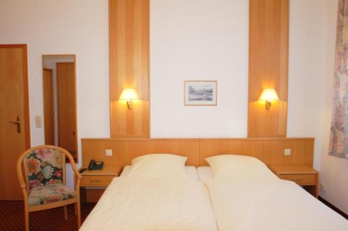 德累斯顿卡登膳食公寓酒店的一间卧室配有一张床、一把椅子和两个灯