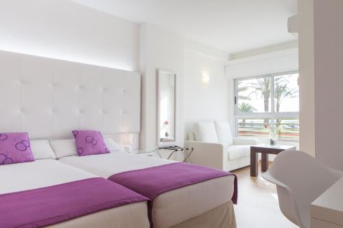 阿利坎特阿利坎特阿巴西亚酒店的白色卧室配有一张带紫色枕头的大床