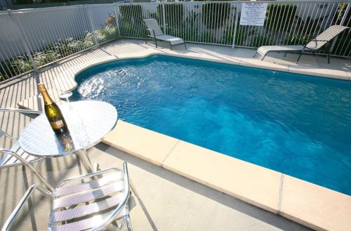 黄金海岸太平洋海岸汽车旅馆的一个带桌子和一瓶葡萄酒的游泳池