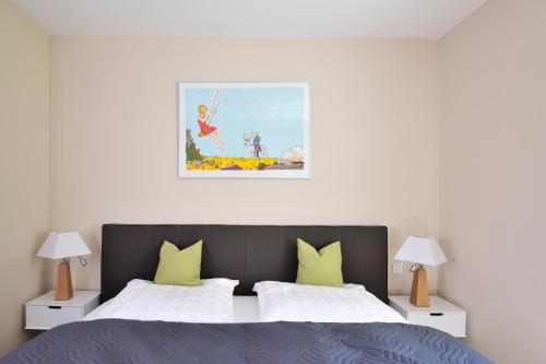 海利根达姆Linden Palais Heiligendamm Apartments的卧室配有一张床,墙上挂有绘画作品