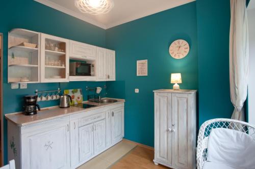 克雷尼察Trzy Siostry的厨房配有白色橱柜和蓝色的墙壁