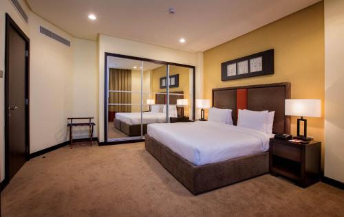 麦纳麦Orange Suites Hotel的一间卧室设有一张大床和一个大镜子