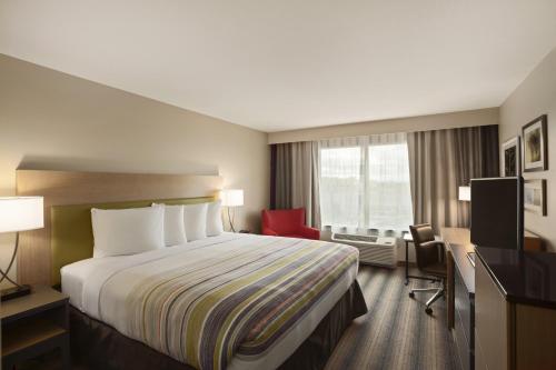 圣安东尼奥Country Inn & Suites by Radisson, San Antonio Medical Center, TX的酒店客房设有一张大床和一张红色椅子。
