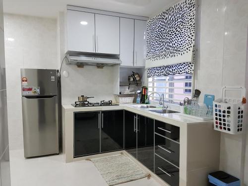 龙运乌米宾馆的厨房配有白色橱柜和不锈钢冰箱