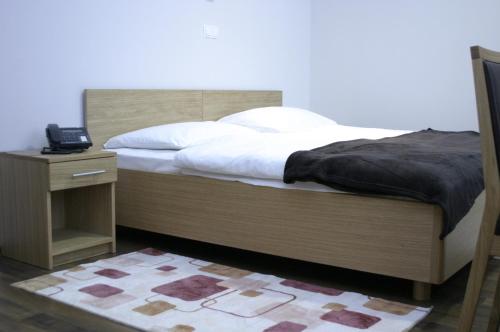 维罗维蒂察维罗维蒂察旅馆的一张带木制床头板的床和一个带电话的床头柜