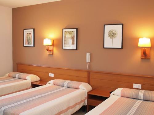 卡拉费尔Hotel El Castell的墙上有三盏灯,房间里有三张床
