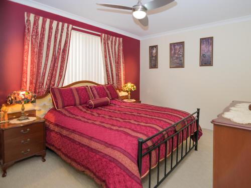 珀斯阿斯科特天鹅住宿加早餐旅馆的一间卧室配有一张大床和红色的床罩