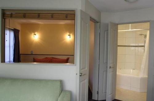 基督城雅典娜汽车旅馆的一间带镜子和浴缸的浴室以及一间卧室