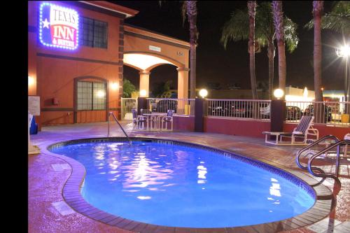 麦卡伦Texas Inn & Suites McAllen at La Plaza Mall and Airport的夜间在酒店前的游泳池
