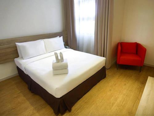 关丹卢舍那客房酒店的酒店客房,配有一张床和一张红色椅子