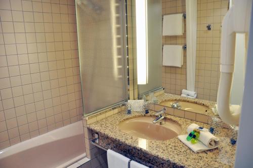安道尔城诺富特安道尔酒店的一间带水槽、浴缸和镜子的浴室