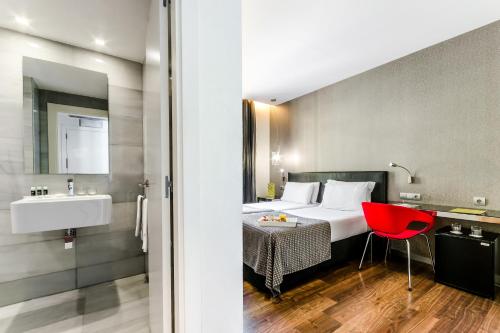 巴塞罗那埃克兰布拉斯博科瑞雅酒店的酒店客房,配有一张床和一张红色椅子