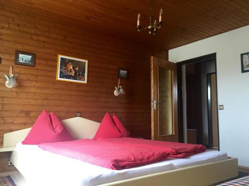 萨尔茨堡豪斯肯恩史托克酒店的木制客房内的一张带粉红色枕头的床