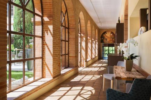 蒙托邦Abbaye des Capucins Spa & Resort的走廊设有窗户和桌椅