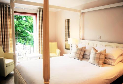 本泰兰金斯伍德酒店的一间卧室配有一张天蓬床和窗户