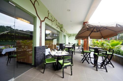 恩德培恩德培最佳西方精品花园酒店的一间带桌椅和遮阳伞的餐厅