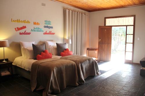 AugrabiesAugrabies Valle Guesthouse的一间卧室配有一张带红色枕头的床